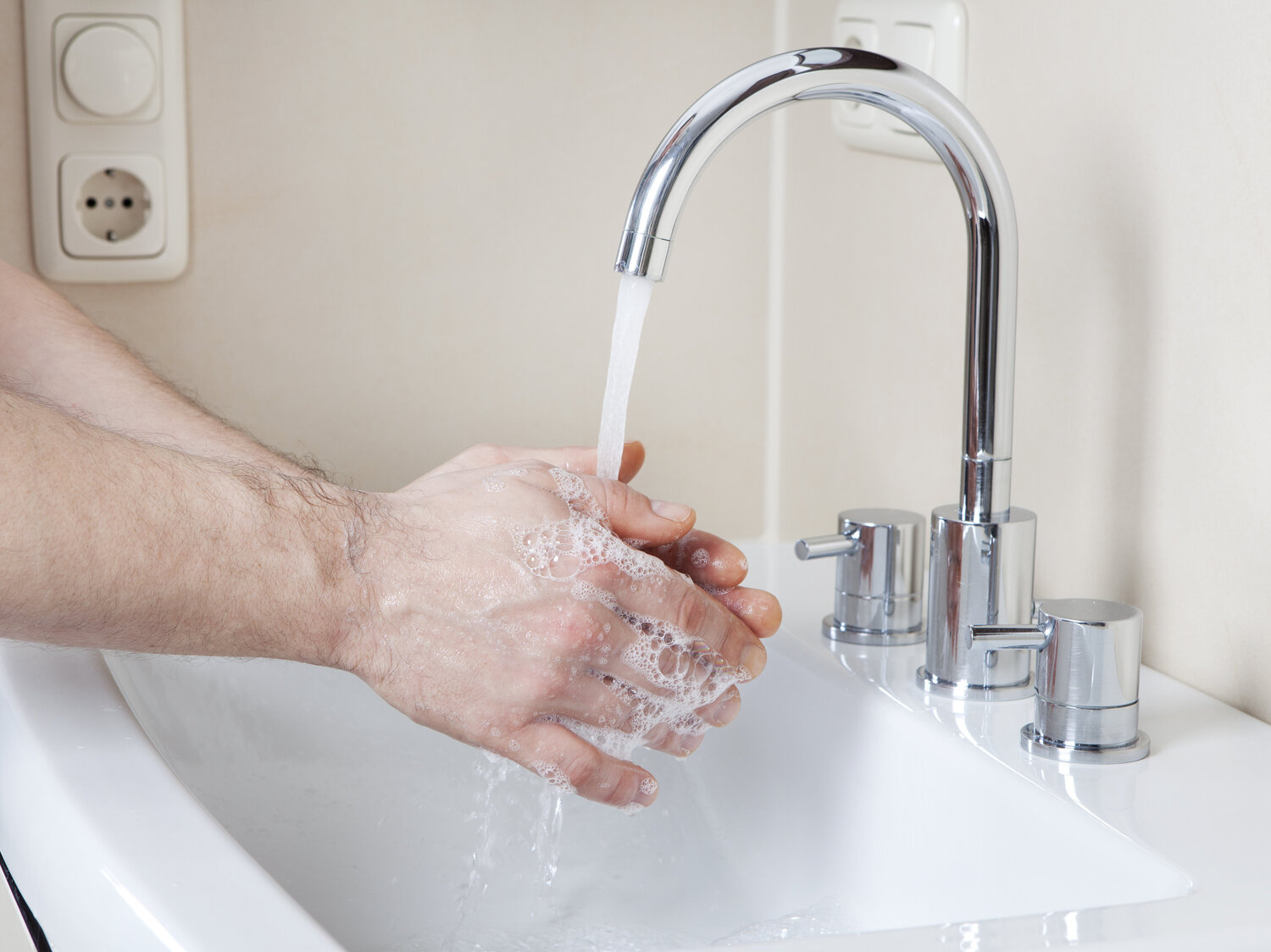 Ein Mann wäscht sich die Hände am Waschbecken